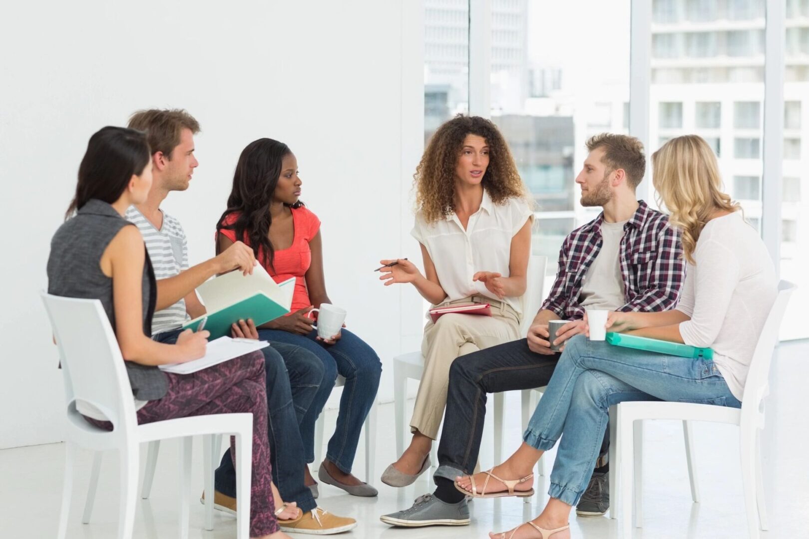 A group of people sitting in chairs talking.